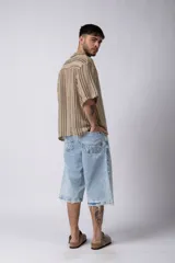 Camisa de manga corta con cuello solapa, corte holgado y estampado de rayas verticales en tonos beige, negro y rojo.