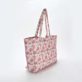 Bolso shopper acolchado con estampado floral en tonos rosa y beige, con doble asa de hombro.