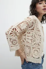 Chaqueta corta color beige, tejida a crochet con diseño floral.