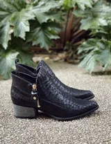 Botín de cuero color marrón claro, con punta fina, cierre lateral con cremallera dorada, detalle de pespuntes en el empeine y taco cuadrado de madera color negro.