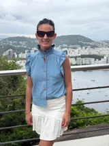 Blusa de denim celeste con cuello mao, mangas cortas con volados y cierre frontal con botones.