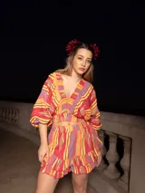 Top corto color crema con estampado de cachemir en tonos naranja y rosa, escote elástico con volantes, mangas cortas abullonadas y corte crop.