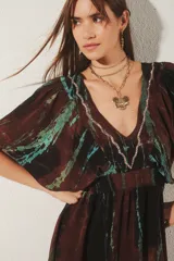 Vestido corto con escote en V y mangas cortas amplias, con elástico fruncido en la cintura. Presenta un teñido tie-dye en tonos marrón oscuro y verde azulado, con bordado de hilos de lurex en el escote.
