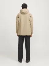 Parka larga color beige con capucha ajustable, cierre frontal con solapa cortaviento, bolsillos funcionales y puños de canalé.