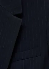 Blazer negro con raya diplomática, cuello de pico con solapa, cierre de botones en la parte delantera, manga larga con puños abotonados, diseño recto y estructurado, un bolsillo de ribete en el pecho y dos bolsillos de ribete con solapa laterales.