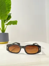 Lentes de sol rectangulares con montura de acetato negra y lentes marrones degradé.