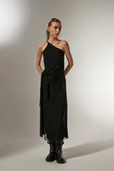 Vestido midi negro de bretel fino, con corte al cuerpo, cuello asimétrico y detalle de nudo en la cintura.