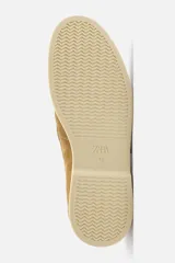 Mocasín casual de hombre color beige, fabricado en piel serraje, con corte liso, detalle de bordón y suela a contraste.
