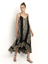 Vestido largo negro con estampado dorado, de breteles finos y escote en V. Presenta una silueta amplia con caída fluida y detalle de volado en el ruedo, ideal para un look relajado y elegante.
