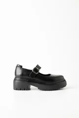 Mocasín negro de cuero con hebilla plateada y suela track.