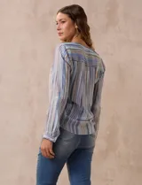 Blusa de gasa estampada a rayas verticales en tonos celeste, lila, naranja y marrón. Tiene cuello a la base con escote en V y botones. Delantera con bolsillo aplicado. Largo de manga regulable con presilla y botón. Terminación anudada opcional.