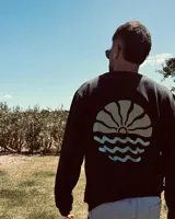 Buzo negro con estampa de sol naciente y olas en la espalda.