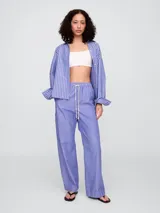 Pantalón de popelina con diseño de rayas verticales en azul y blanco, de corte recto y holgado con cintura elástica y cordón ajustable.