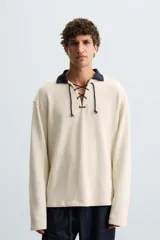 Sudadera color crema de tejido con estructura vertical, corte relaxed fit, cuello polo combinado en color azul marino y ajuste frontal con cordón.
