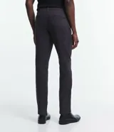 Pantalón de vestir color beige, de corte slim, con bolsillos laterales y traseros. Se ajusta a la cintura con cinturón de cuero negro.