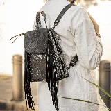 Mochila de cuero vacuno negro, con cierre superior, broche a presión y múltiples bolsillos interiores.