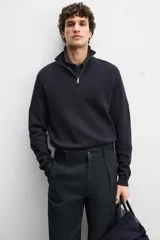 Jersey negro de punto de algodón, corte recto, cuello perkins con cremallera metálica y mangas largas terminadas en rib.