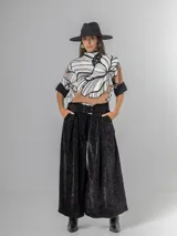 Pantalón ancho de corderoy negro con pliegues marcados en la parte delantera y cintura elástica. Incluye un cinturón negro con hebilla cuadrada.