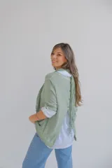 Sweater verde con cuello alto, mangas 3/4 y bajo asimétrico. Incluye una camisa blanca de mangas largas y una bufanda de encaje verde.