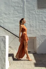 Vestido largo color ladrillo, de un solo hombro, con abertura cut-out en la cintura y falda irregular con frunces.