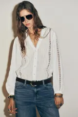 Blusa blanca de manga larga con escote en pico, detalle de tejido con frunces, entredoses y plumeti. Cierre frontal con botones.