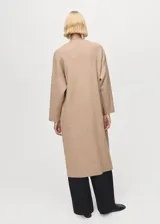 Abrigo largo de tejido de punto color beige, sin cierre, con cuello solapa y manga larga.