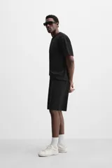 Bermuda negra de corte relaxed fit, con cintura elástica ajustable con cordón, bolsillos frontales y bolsillo trasero de parche.