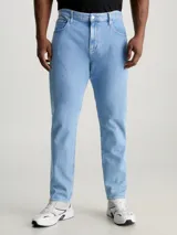 Jeans celeste de corte slim fit, tiro medio y pierna cónica. Diseño clásico de cinco bolsillos, con cierre de botón y cremallera.