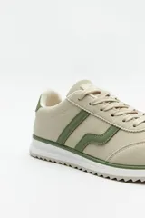 Zapatillas beige con recortes en gamuza de diferentes tonos, cordones y suela irregular blanca con detalle rosa.
