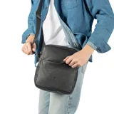 Bandolera negra de cuero con correa ancha de tela con el logo de la marca.