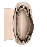 Cartera Guess modelo Sora Chica, color beige, con correa de hombro ajustable y logo triangular dorado en el frente.