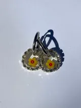 Aros dorados con dije circular de resina y strass, con flor de vidrio verde en el interior. El arito es de acero quirúrgico.