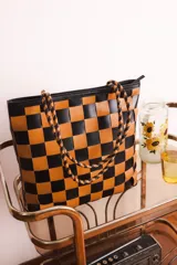 Bolso tipo tote de cuero tejido a mano con diseño a cuadros en color negro y tostado.