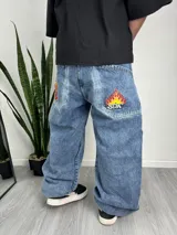 Pantalón de jean celeste con corte holgado y parches bordados de llamas en los bolsillos traseros.