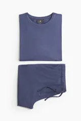 Conjunto de pijama azul de dos piezas en tejido de punto. Incluye una remera de manga corta con cuello redondo y un short con cintura elástica ajustable con cordón y bolsillos laterales.