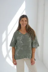 Blusa verde con estampado de flores blancas, cuello en V y mangas cortas.
