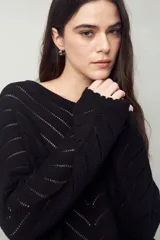 Sweater negro calado con diseño de líneas diagonales en relieve y mangas acampanadas.