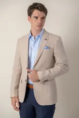 Saco de lino color beige, corte slim fit, con solapa de muesca, cierre de dos botones, bolsillo en el pecho y dos bolsillos delanteros con solapa. Medio forro.
