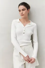 Sweater blanco de punto acanalado con cuello tipo polo y botonadura frontal de botones metálicos. Mangas largas con terminación en pequeñas aberturas.