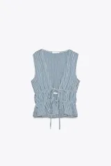 Top amarillo con estampado de cuadros vichy blancos, escote en pico, sin mangas, con detalle de elásticos en la cintura y cierre frontal con lazadas.