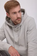 Hoodie tipo canguro color gris mineral, de manga larga con capucha y fit regular. Cuenta con un bolsillo y estampado de goma con tacto suave. Tejido Loop Back.