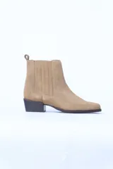 Botín de gamuza color beige con elásticos laterales, punta fina y taco cuadrado bajo.