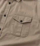 Camisa verde militar de manga larga en sarga de algodón, con cuello clásico, cierre frontal abotonado y dos bolsillos con solapa abotonada en el pecho.