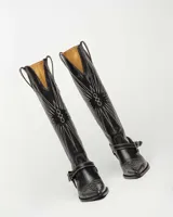 Bota de cuero negro con diseño ranchero, caña alta y puntera fina, con detalle de hebilla.