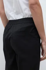 Pantalón negro de vestir, tiro alto, con pinzas frontales y corte ancho y holgado.