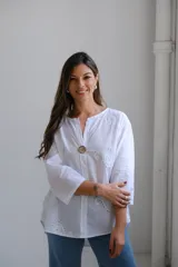 Blusa blanca de mangas largas con cuello mao y cierre frontal con botón de madera.
