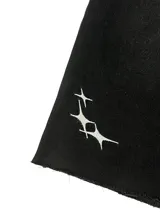 Bermuda de jean negra de corte ancho (baggy) y largo 3/4, con bordados de estrellas blancas en la parte inferior de la pierna izquierda.