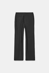 Pantalón negro de tejido fluido, tiro medio, cintura elástica ajustable con cordones y bolsillos laterales ocultos en la costura.