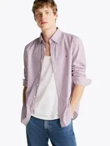 Camisa Tommy Hilfiger de corte regular, confeccionada en popelina de algodón a rayas verticales rojas, azules y blancas. Cuenta con cuello abotonado, mangas largas con puños abotonados, logo bordado en el pecho y tecnología Flex para mayor comodidad.