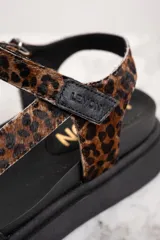 Sandalia de cuero con diseño de animal print y suela negra, con tiras ajustables.
